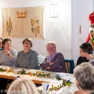Ein verkleideter Nikolaus kommt durch eine Tür und überraschte Menschen wenden sich ihm zu