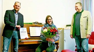 Mit Blumen und Urkunde überraschten Dekan Tobias Schäfer (links) und Pfarrer Thomas Lichteneber (rechts) Kantorin Heidi Brettschneider.